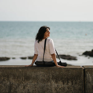 Ladina Yoga Warrior Black travel yoga mat sitting by the beach