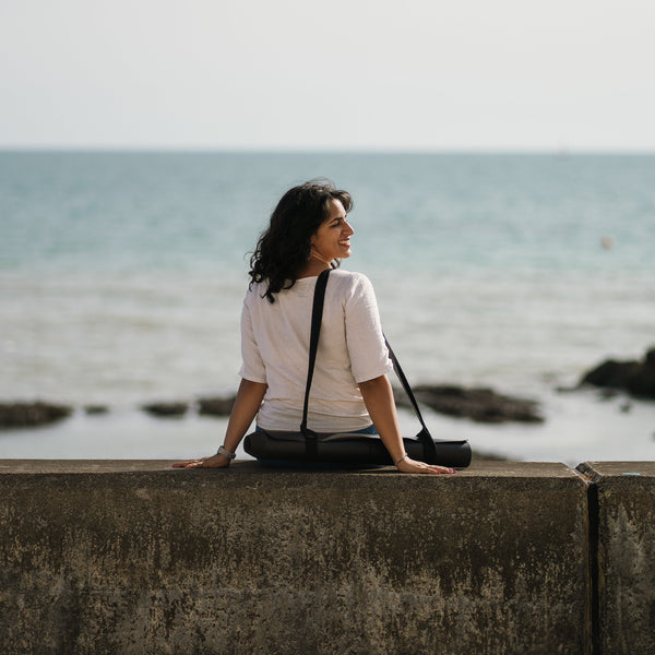 Load image into Gallery viewer, Ladina Yoga Warrior Black travel yoga mat sitting by the beach
