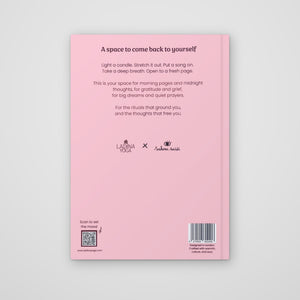 The back cover of a pink journal or notebook on a light gray background. The cover features black text with a title, a short affirmation, and several logos including 'Ladina Yoga' and 'Anubhava Yoga'.