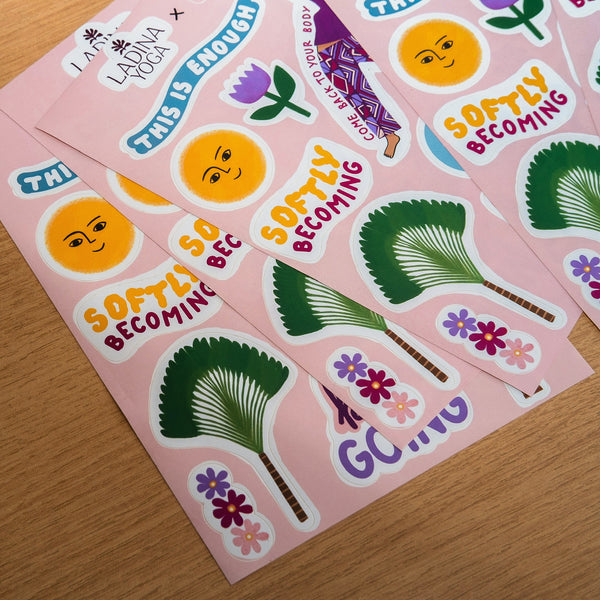 Load image into Gallery viewer, Several pink sticker sheets arranged on a wooden surface, featuring illustrated sun faces, palm trees, flowers, and phrases such as 'SOFTLY BECOMING' and 'THIS IS ENOUGH.'.
