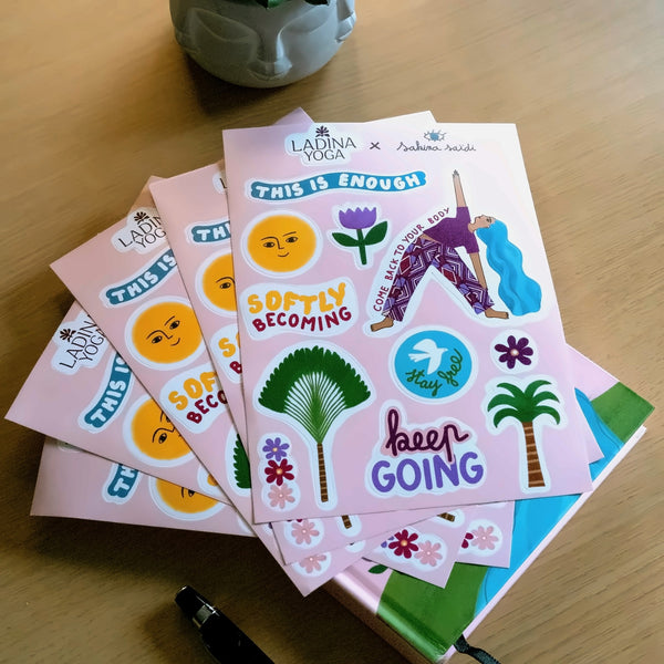 Load image into Gallery viewer, A stack of pink sticker sheets featuring motivational yoga-themed stickers and quotes like 'THIS IS ENOUGH', 'SOFTLY BECOMING', and 'keep GOING', displayed on a wooden tabletop.
